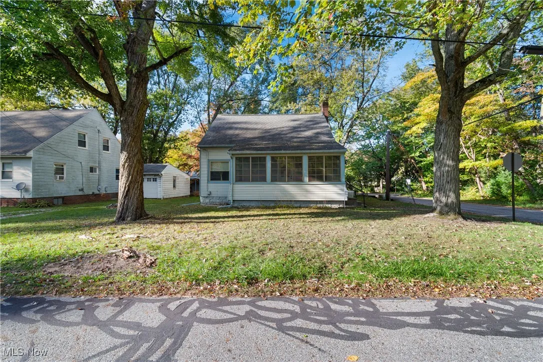 View of front of home with a front yard, a sunroom, and a chimney
