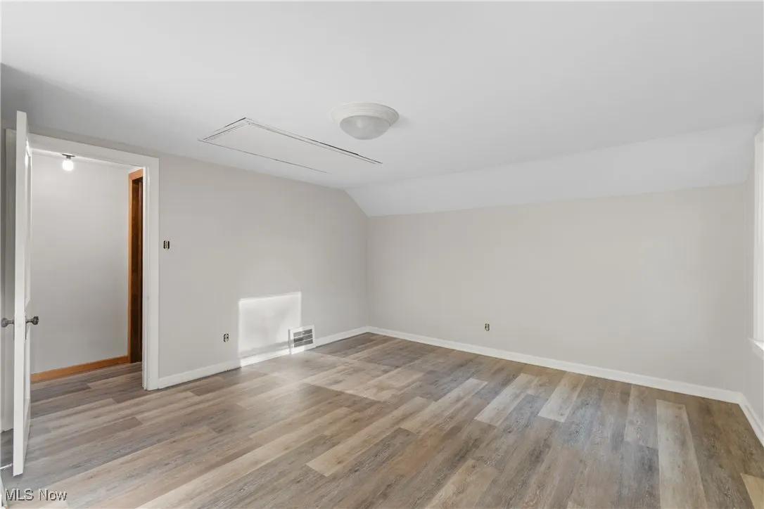 Bonus room featuring attic access, vaulted ceiling, and light wood-style floors