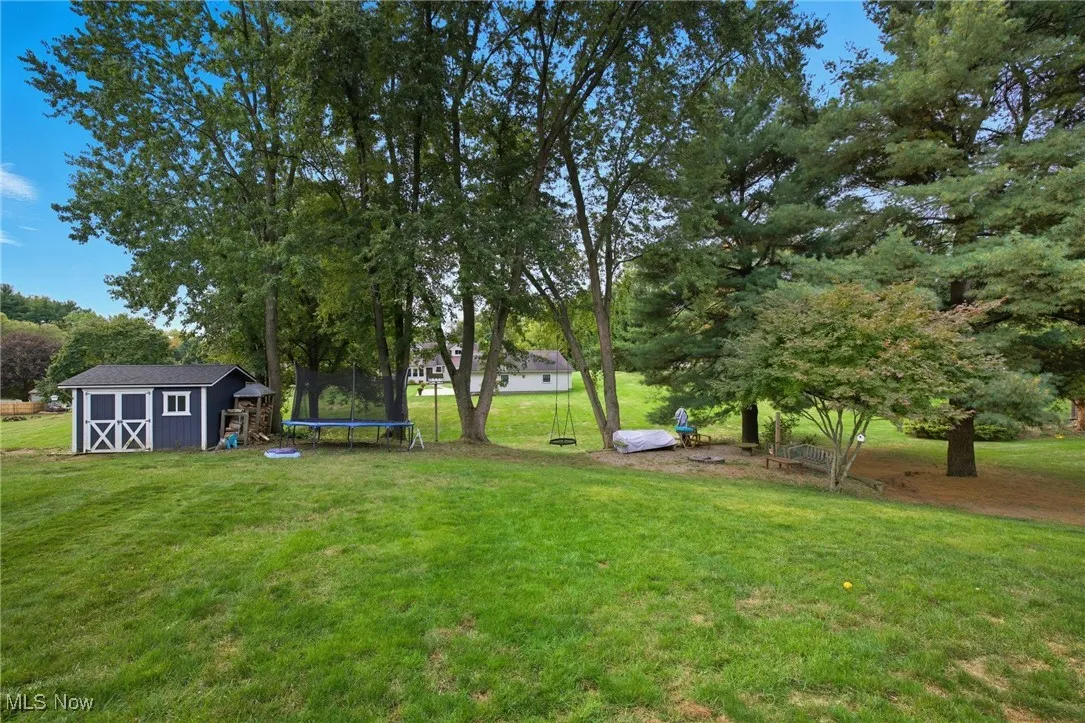 View of the backyard featuring the shed and firepit area