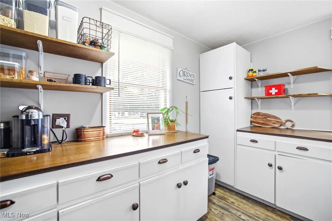Pantry with dark countertops, cabinetry, and open shelves