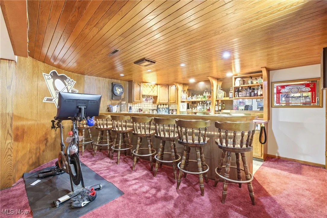 Bar featuring open shelves and wood ceiling/wall