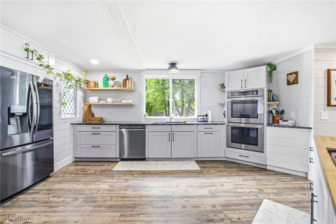 Kitchen with open shelves, cabinetry, stainless steel appliances, and LVT flooring