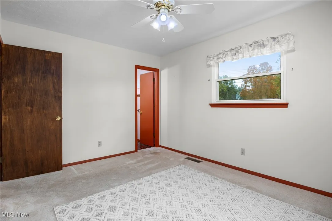 Primary bedroom with two closets, ensuite half bathroom, carpet and ceiling fan