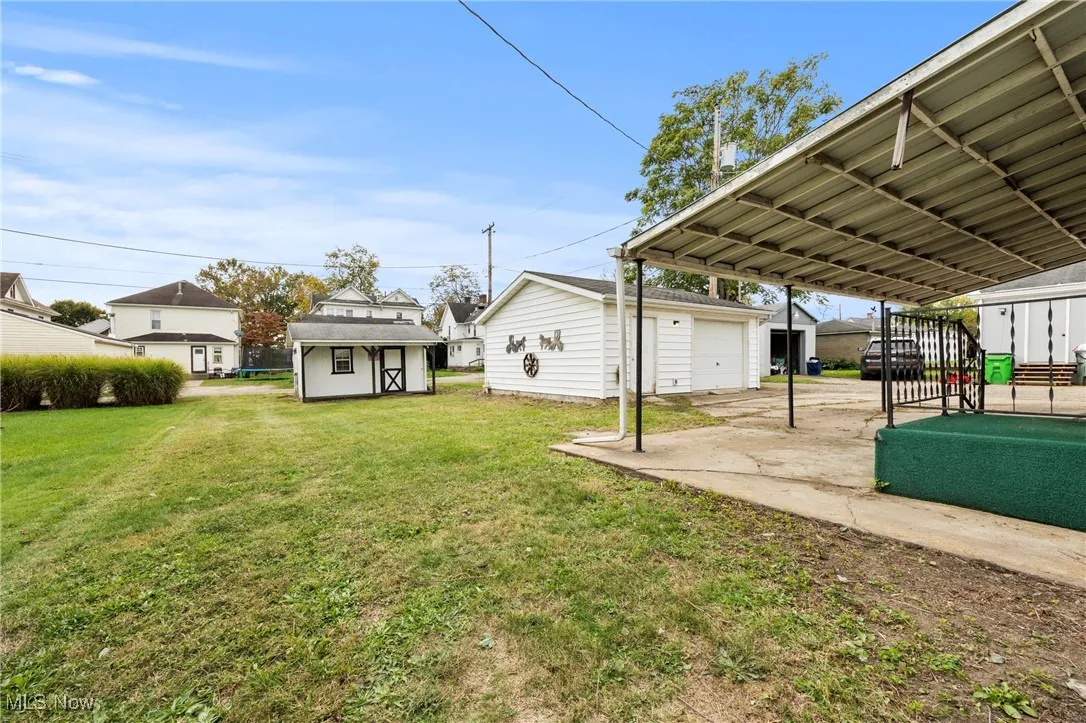 View of green lawn featuring an outbuilding and a detached garage