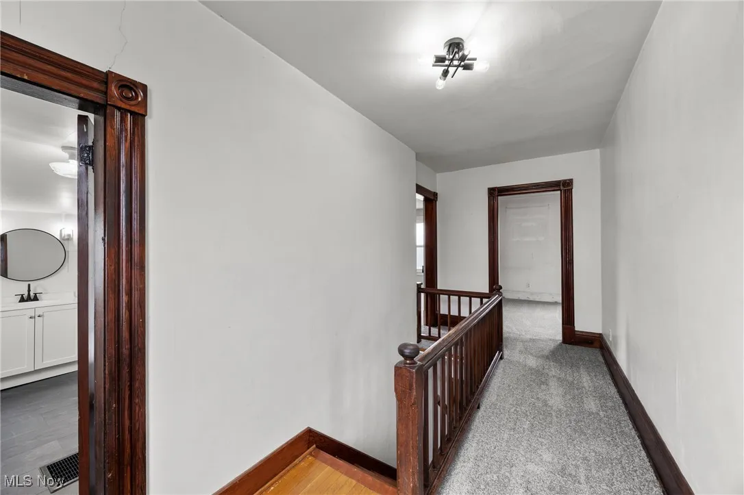 Corridor featuring an upstairs landing and light colored carpet