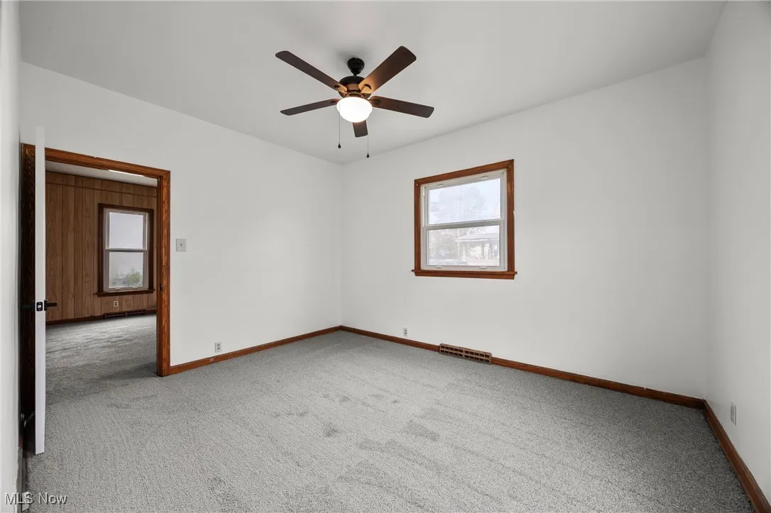 Empty room with light carpet and a ceiling fan