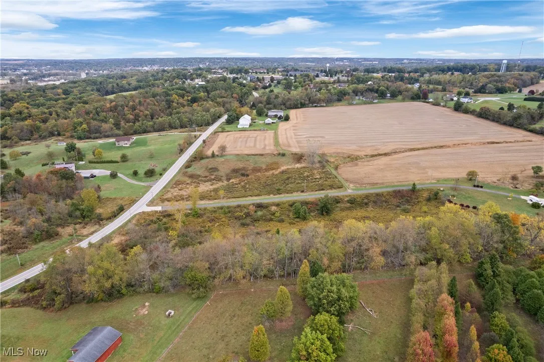 Aerial view of property and surrounding area featuring rural landscape and a tree filled landscape