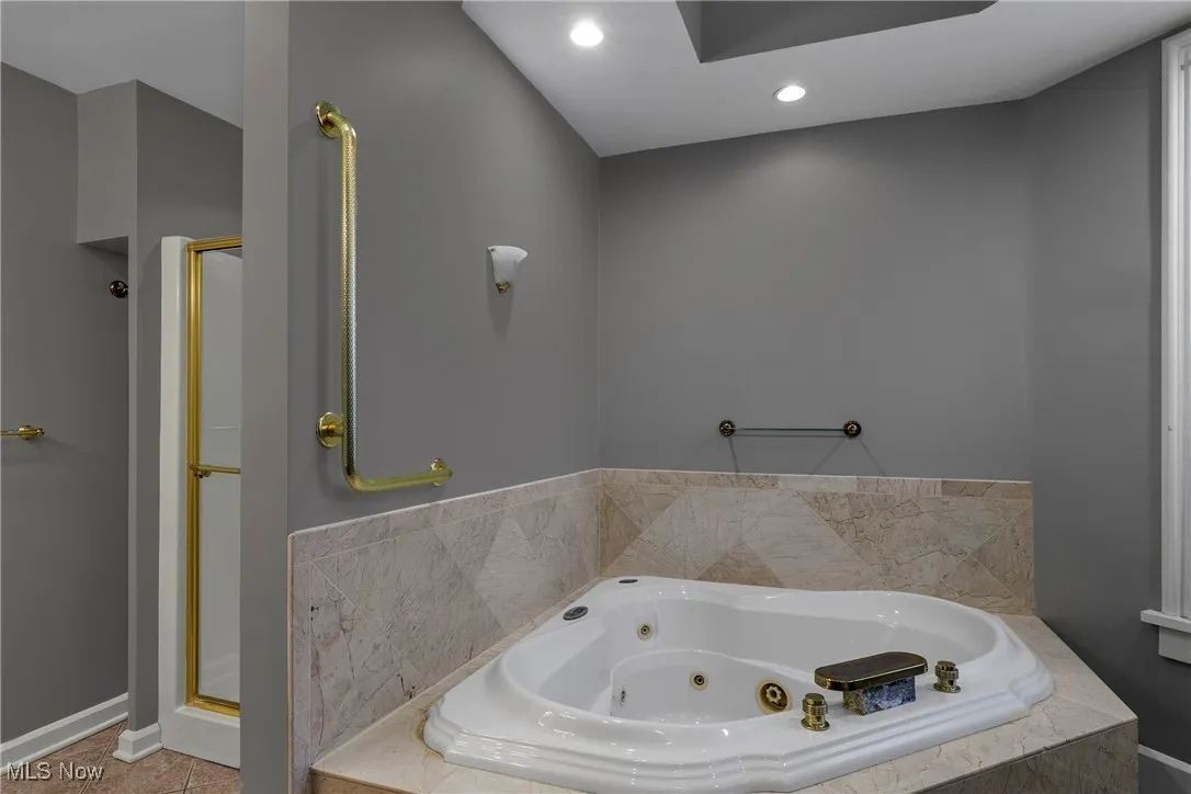 Bathroom with a whirlpool tub, a stall shower, and recessed lighting