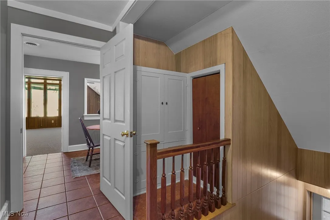 Stairway featuring tile patterned flooring and wooden walls