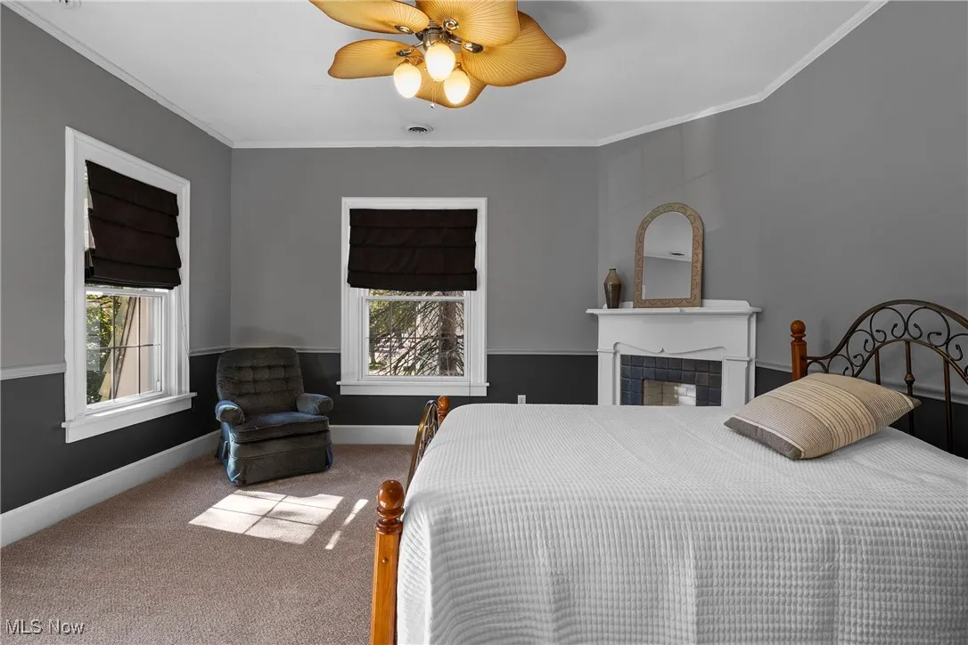 Bedroom featuring carpet floors, crown molding, a ceiling fan, and multiple windows