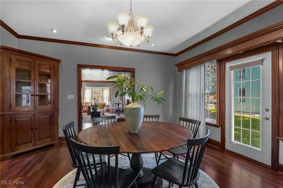 Dining area with crown molding, dark wood-style flooring, and a chandelier