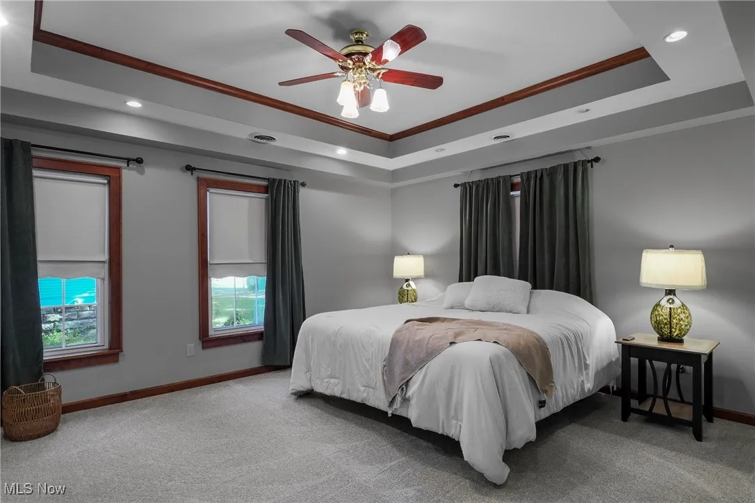 Bedroom featuring a tray ceiling, recessed lighting, carpet flooring, ceiling fan, and ornamental molding