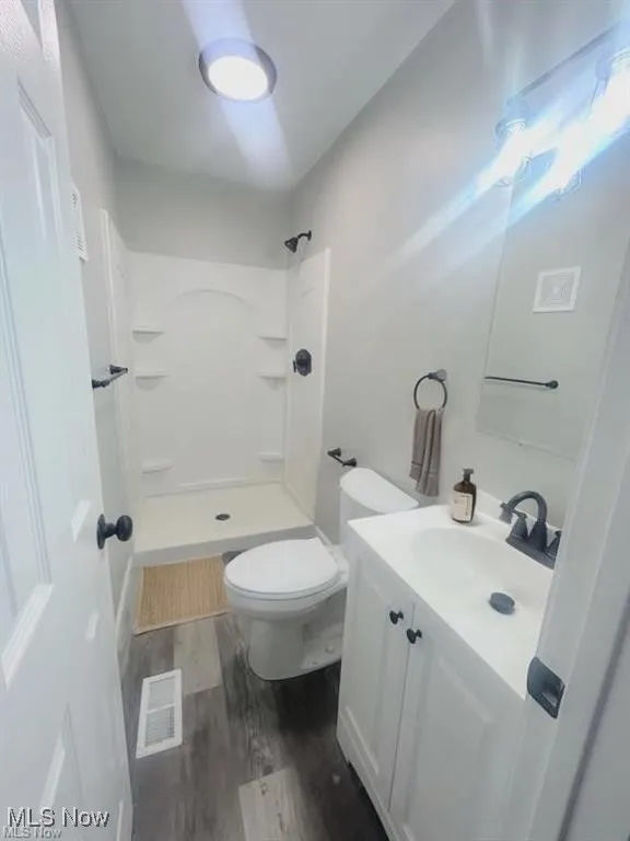 Full bathroom with dark wood finished floors, vanity, and a stall shower