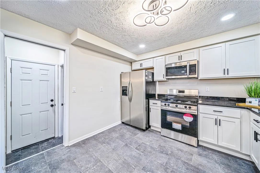 Kitchen featuring white cabinets, appliances with stainless steel finishes, and a textured ceiling