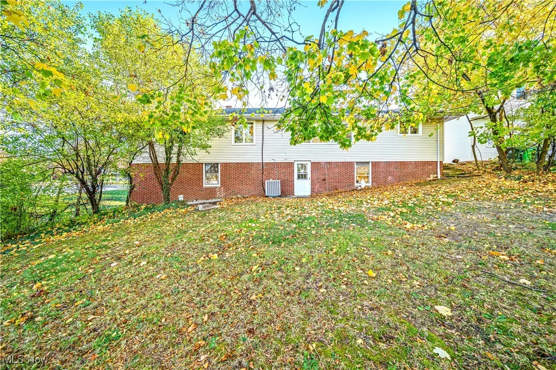 View of side of property featuring central AC and a lawn