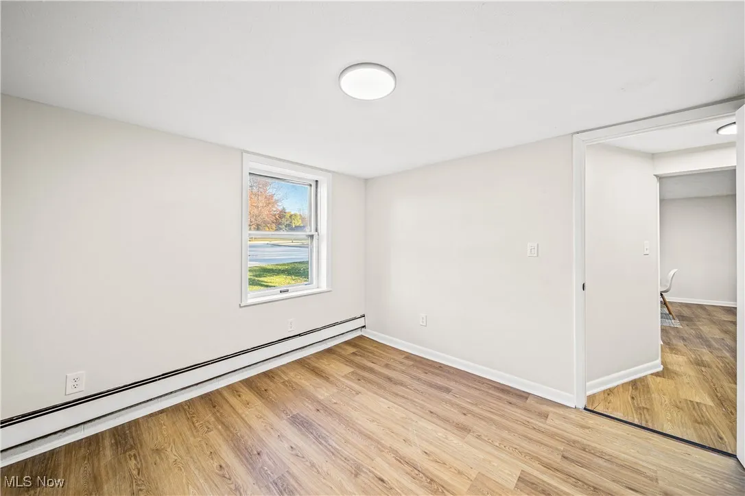Empty room featuring light wood-type flooring and a baseboard heating unit