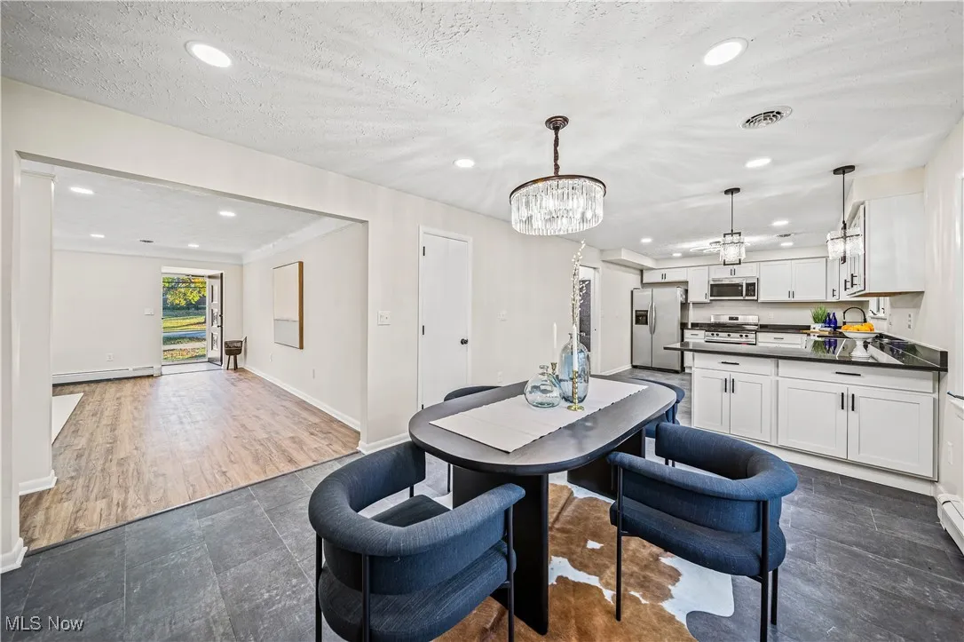 Dining room featuring a textured ceiling, dark hardwood / wood-style floors, a baseboard radiator, and an inviting chandelier