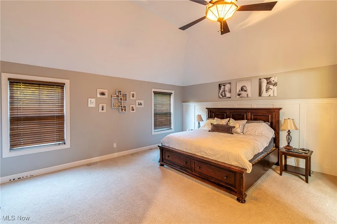 Bedroom 1 featuring vaulted ceiling, carpet flooring, and ceiling fan
