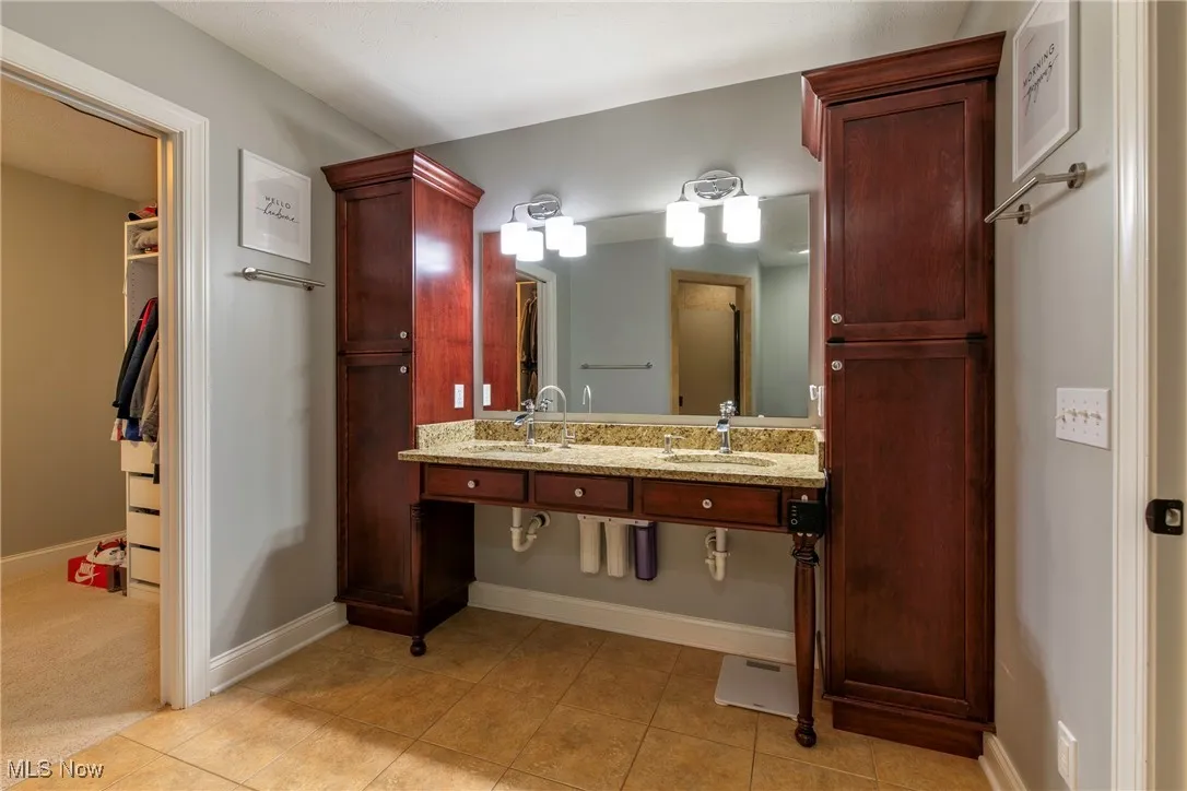 Full bathroom featuring light tile patterned floors, a walk in closet, and double vanity