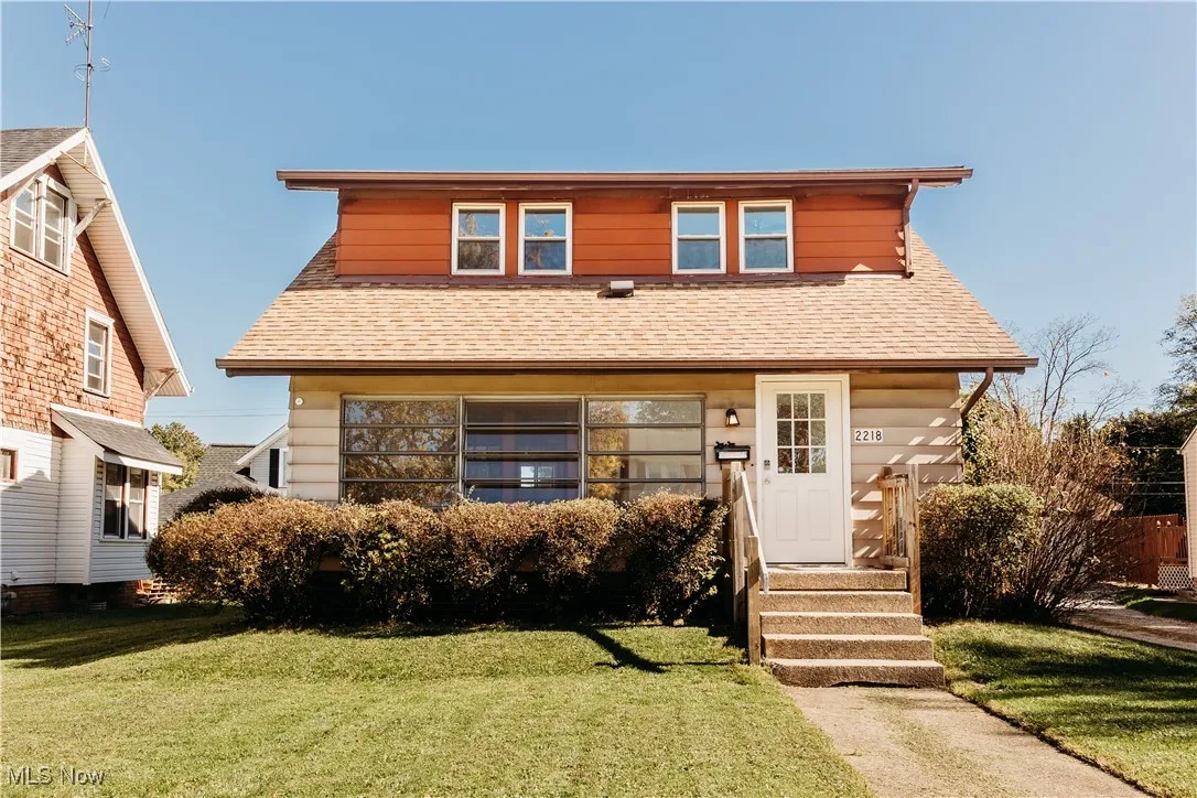 View of front of property with roof with shingles and a front yard