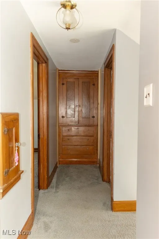 Hallway featuring baseboards and light carpet