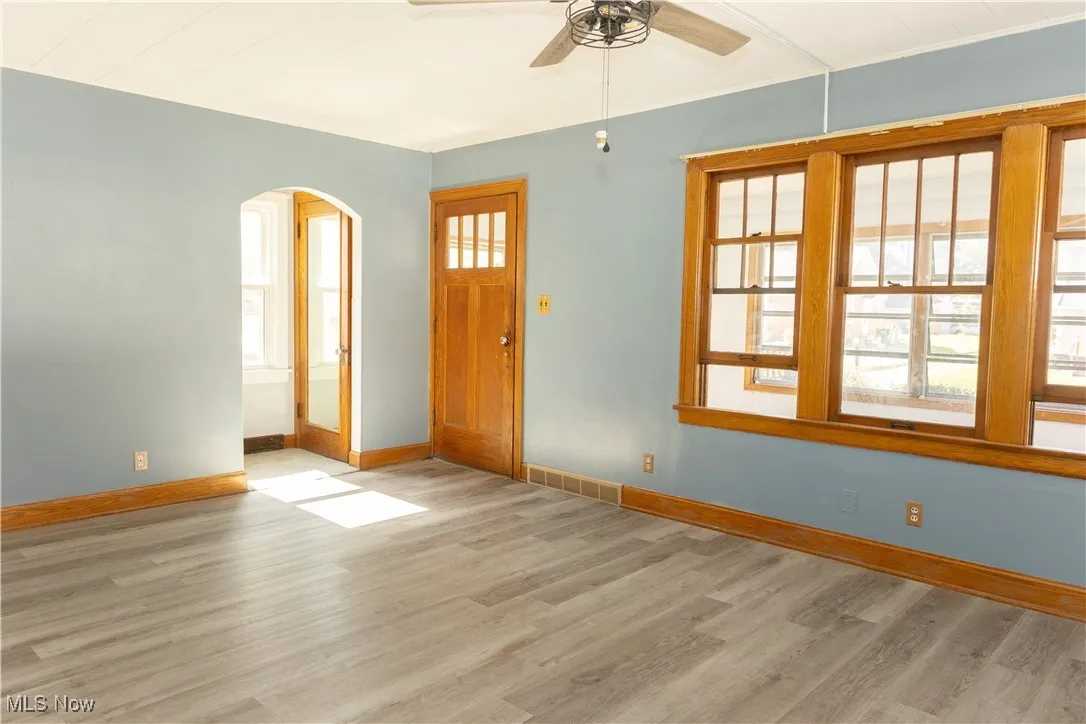Foyer with arched walkways, light wood finished floors, and a ceiling fan