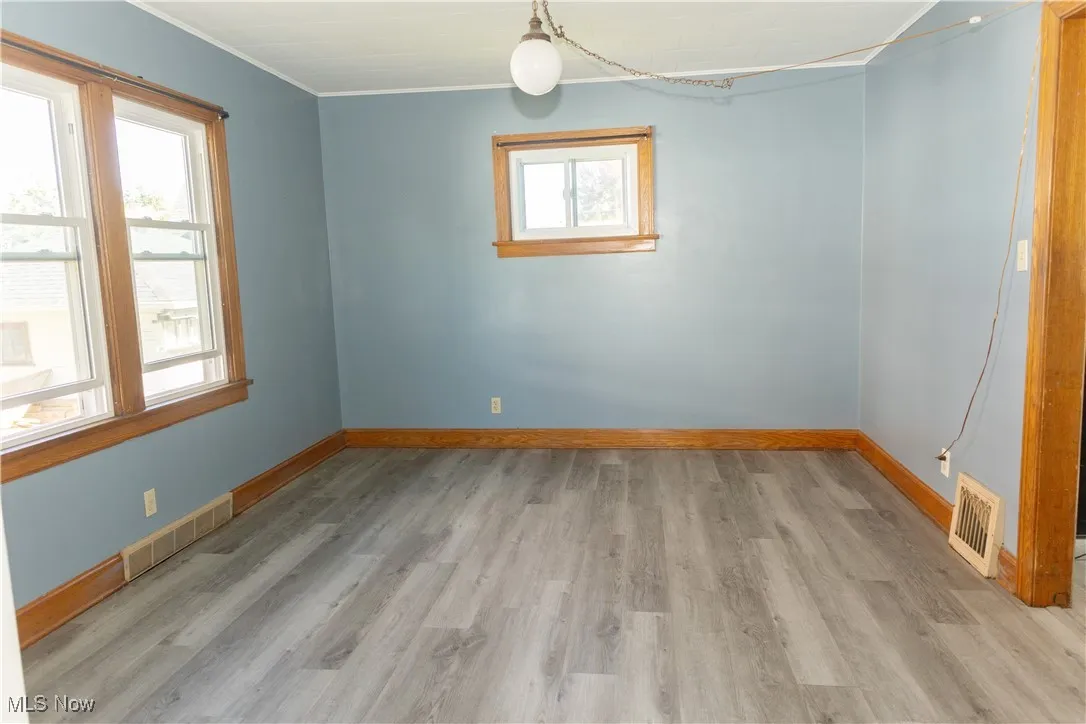 Unfurnished room with light wood-type flooring and crown molding