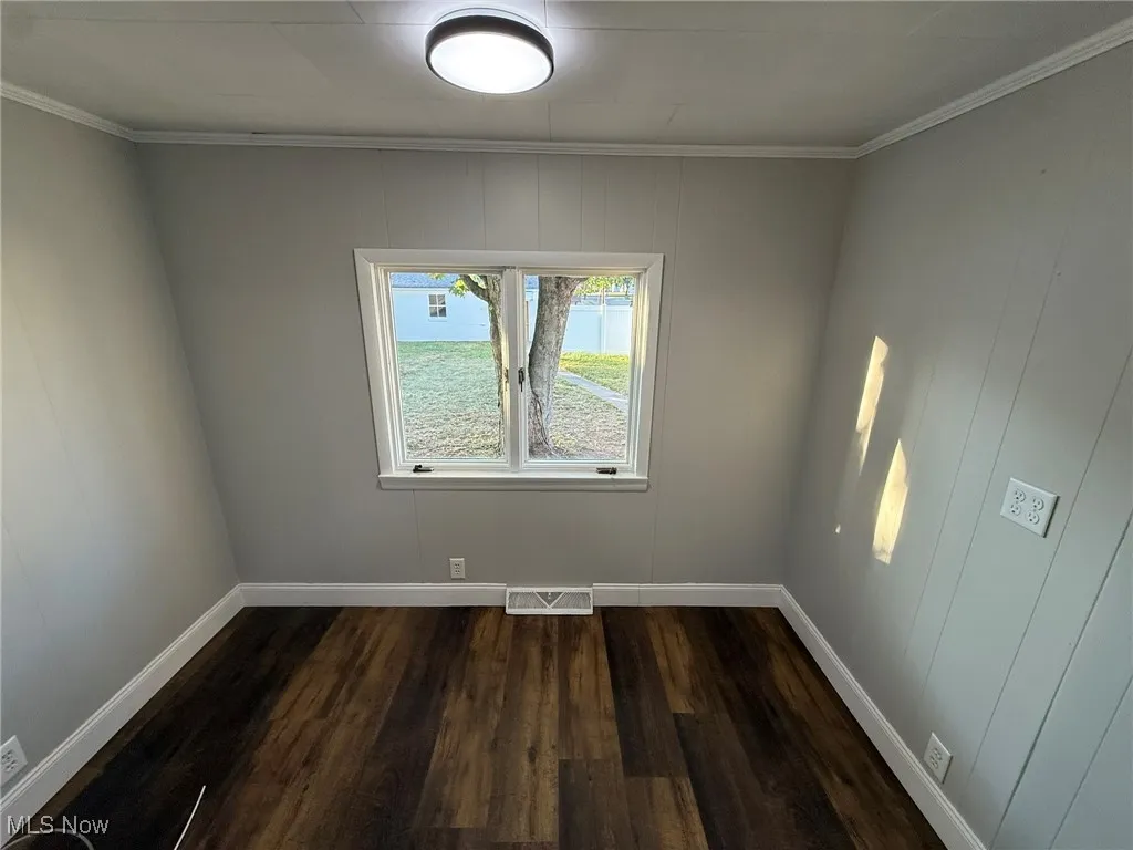 Spare room with dark wood finished floors and ornamental molding