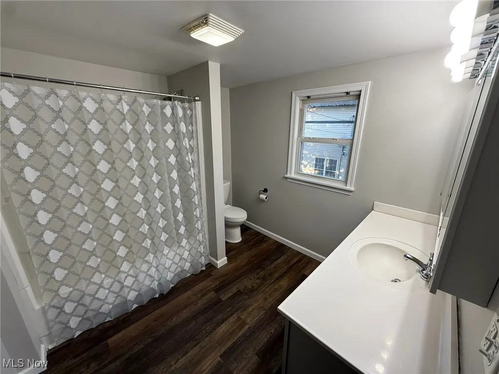 Bathroom with vanity, a shower with curtain, and dark wood-style flooring