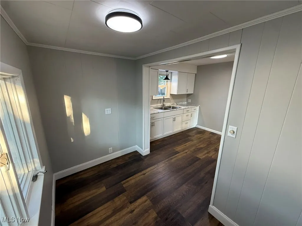 Kitchen featuring crown molding, white cabinetry, light countertops, and dark wood-type flooring