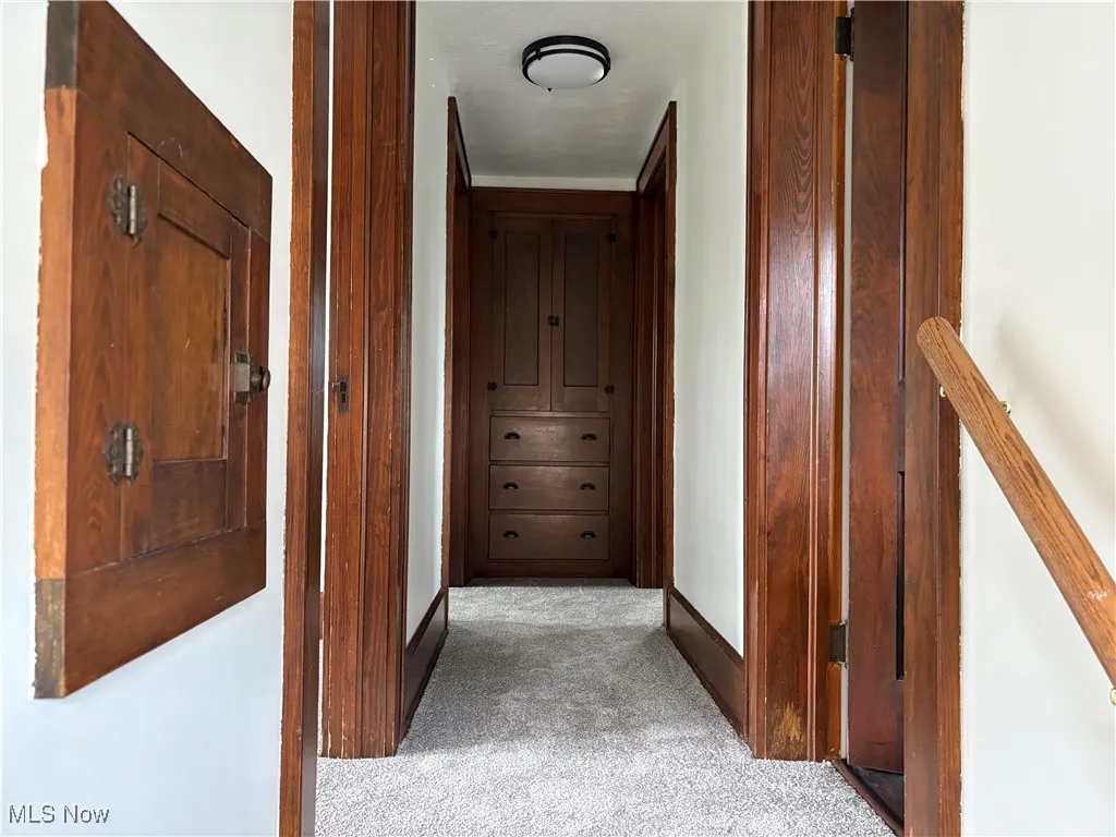 Corridor with light colored carpet and baseboards