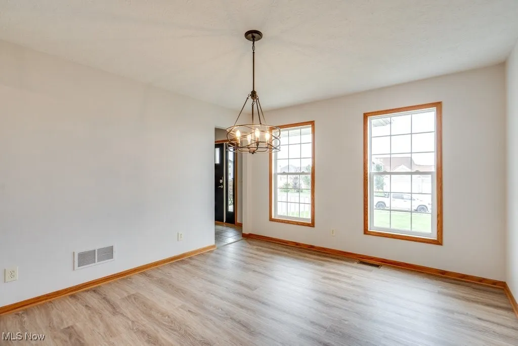 Unfurnished dining area featuring light wood-type flooring and a chandelier