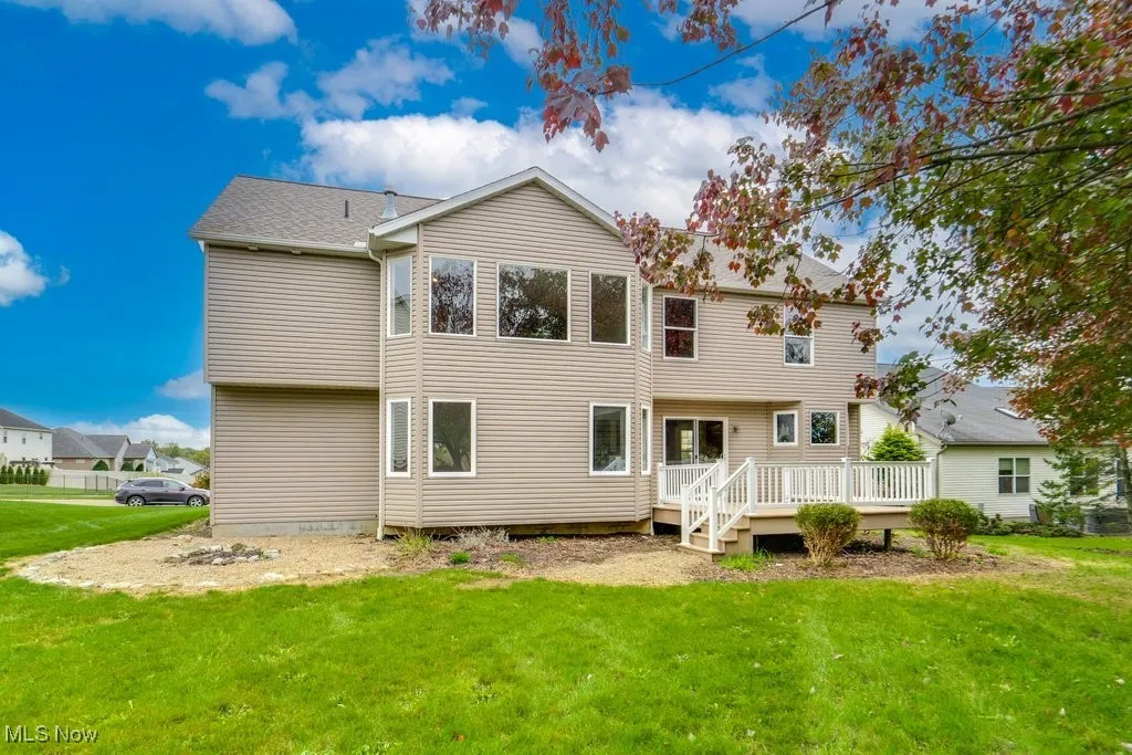 Back of property featuring a wooden deck and a lawn