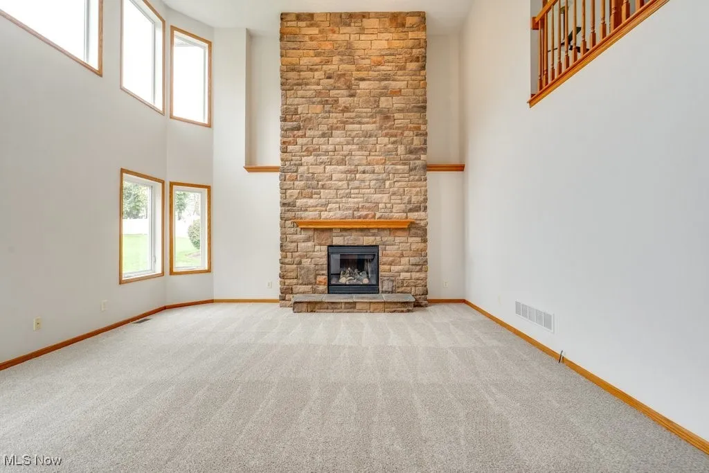 Unfurnished living room featuring carpet flooring, a fireplace, and a towering ceiling