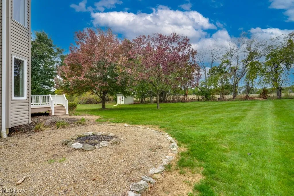 View of green lawn with a wooden deck and a storage unit