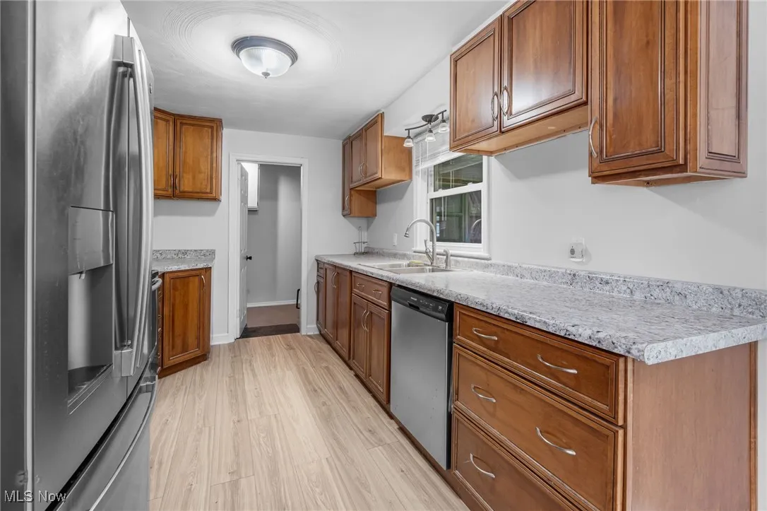 Kitchen featuring appliances with stainless steel finishes, light countertops, brown cabinetry, and light wood-type flooring