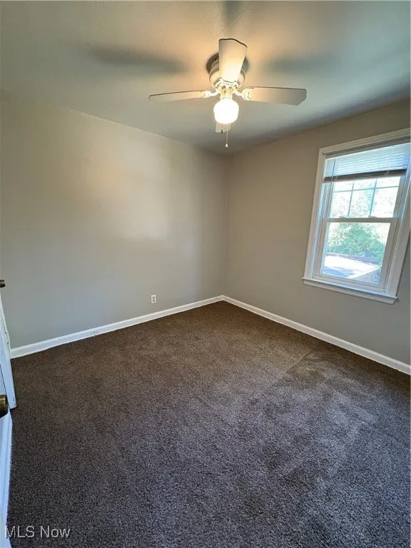 Spare room with dark colored carpet and baseboards