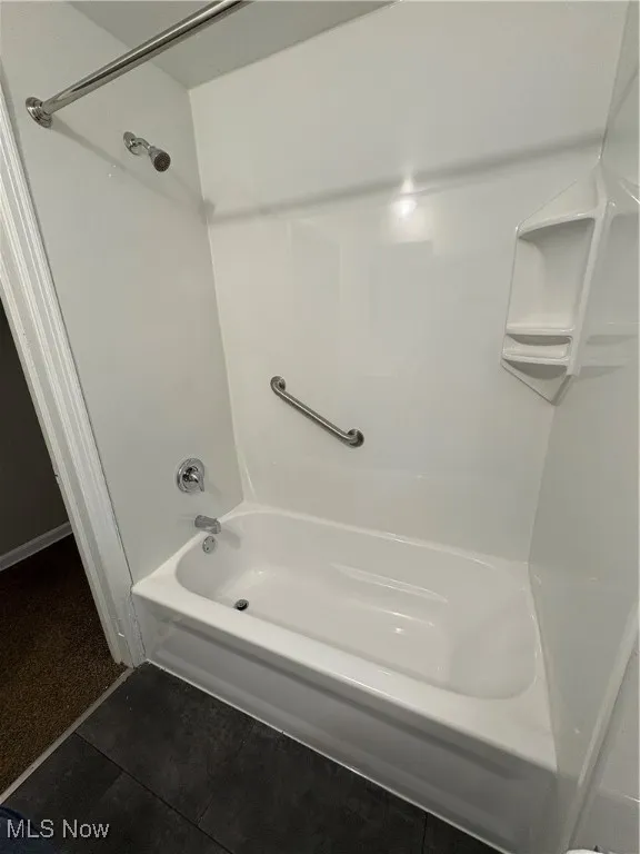 Full bathroom with bathing tub / shower combination and dark tile patterned flooring