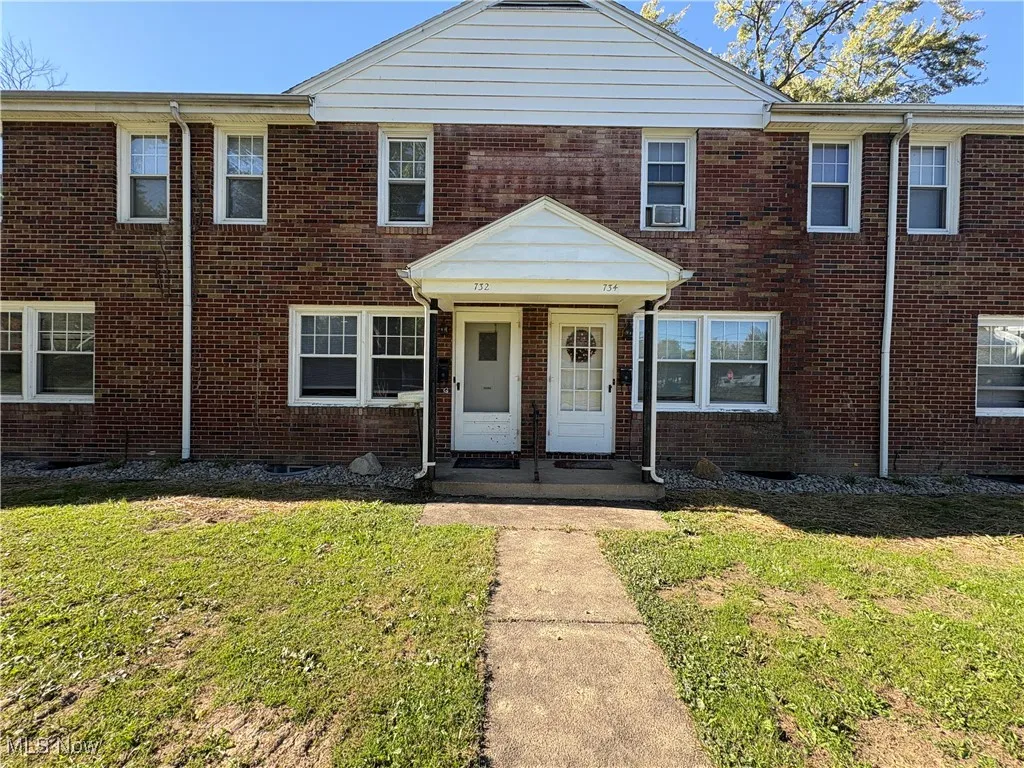 View of front of property featuring brick siding, a front yard, and covered porch