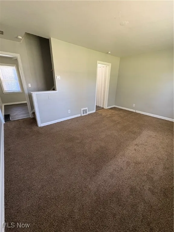 Spare room with dark carpet and baseboards
