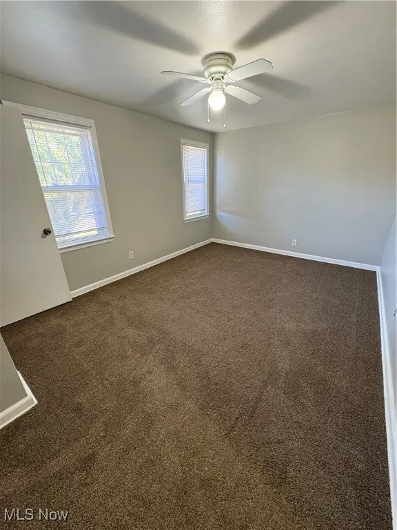 Spare room with dark carpet and ceiling fan