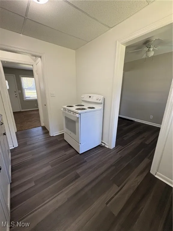 Kitchen featuring white range with electric cooktop, dark wood-type flooring, ceiling fan, and a drop ceiling