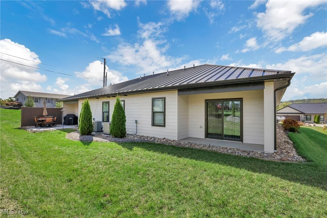 Back of property featuring a patio, a lawn, a standing seam roof, and a metal roof