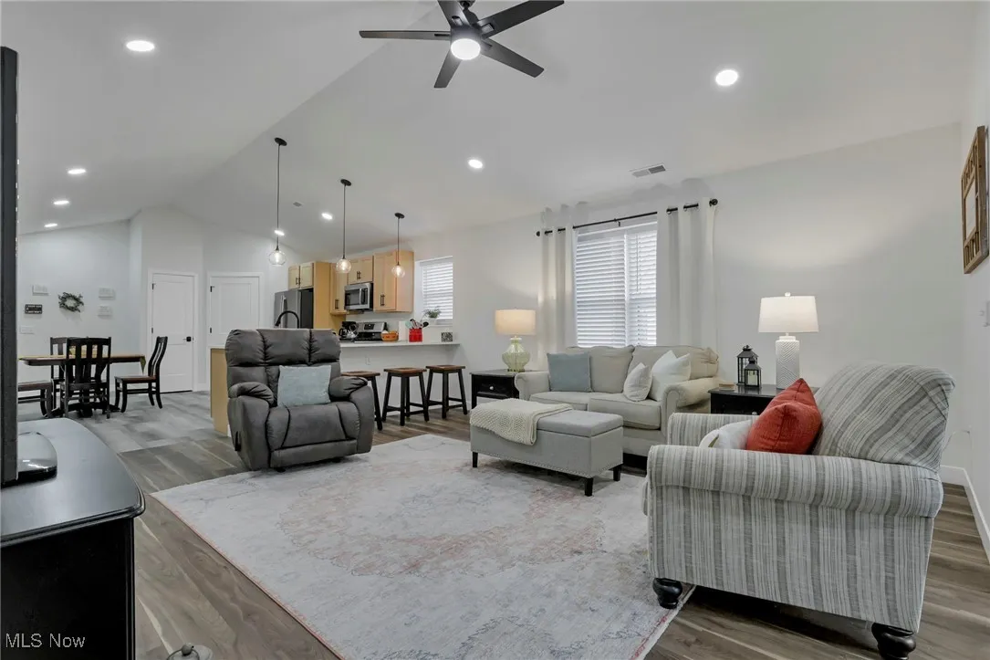Living room featuring LVP floors, ceiling fan, recessed lighting, and high vaulted ceiling