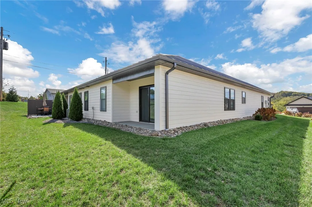 View of side of property featuring a lawn and a patio