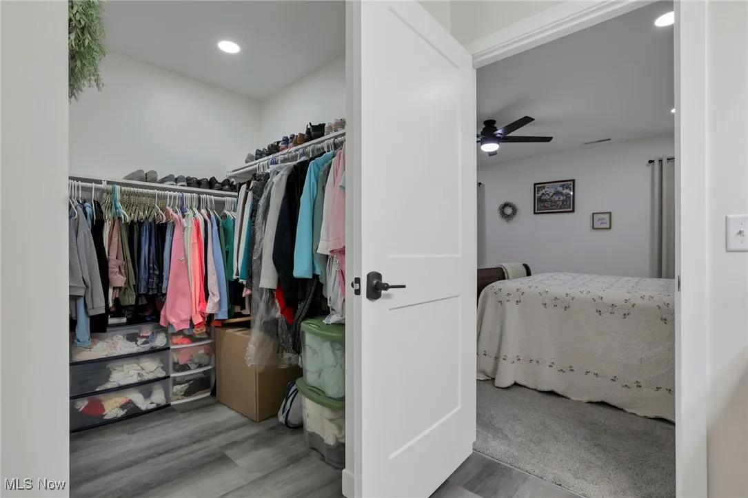 Walk in closet with light wood-type flooring and ceiling fan
