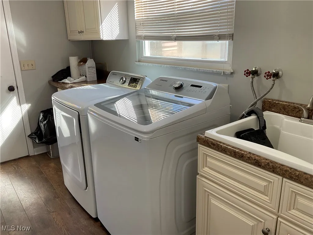 Laundry area with cabinet space, washer and dryer, and dark wood finished floors