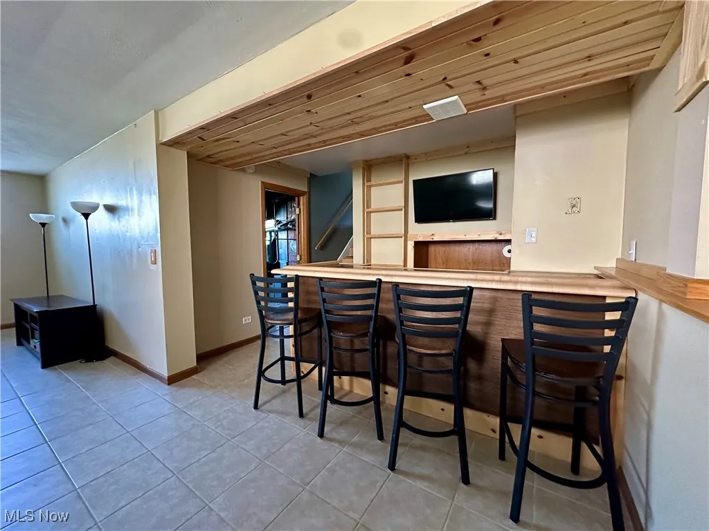 lower level family room ndoor dry bar featuring light tile patterned flooring