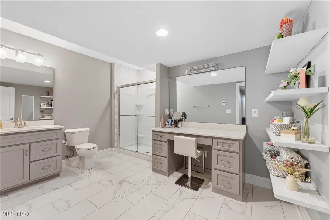 Bathroom with a shower stall, vanity, light marble finish floors, and recessed lighting