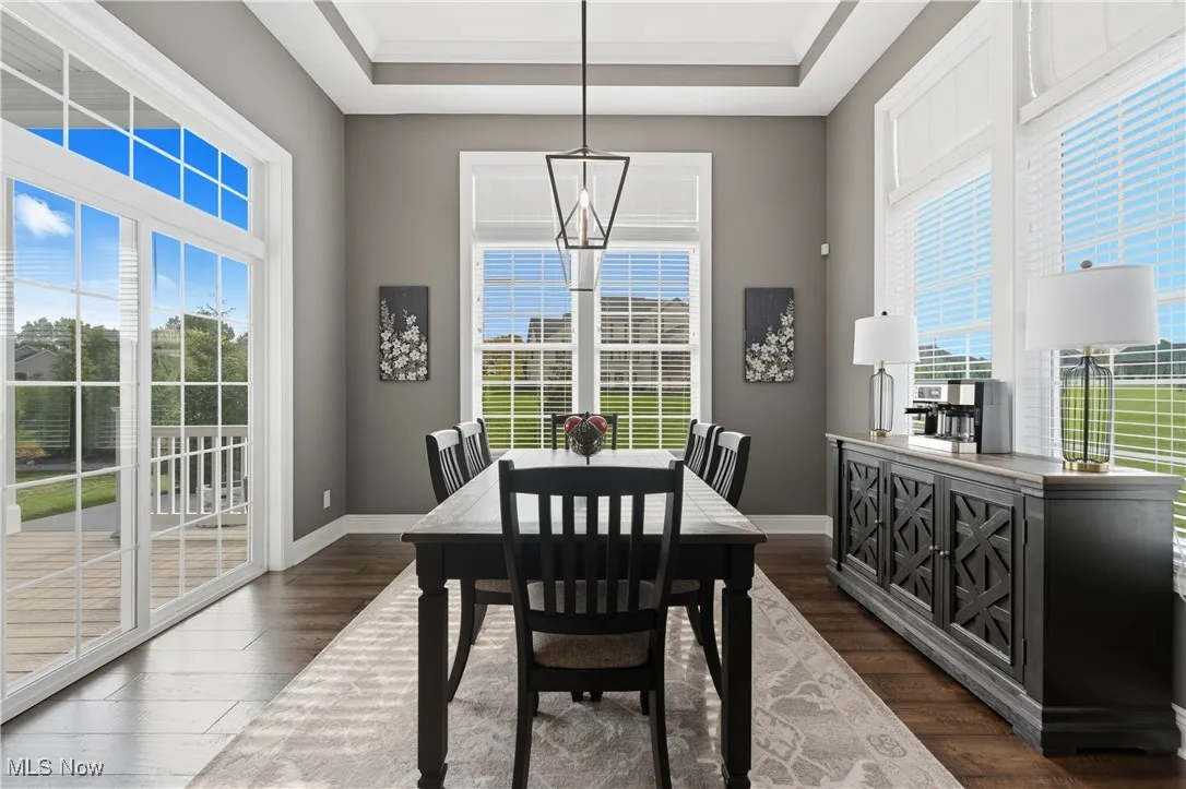 Dining area with dark wood-type flooring, a chandelier, and a raised ceiling